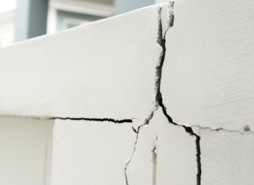 Cracks running through a painted concrete exterior wall on a Florida condominium building