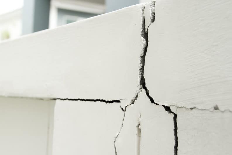 Cracks running through a painted concrete exterior wall on a Florida condominium building